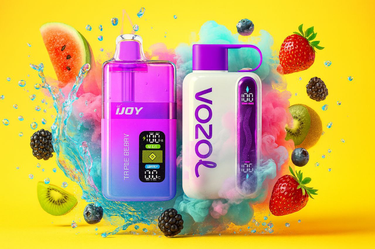 A bright, high-energy product image showcasing two vaporizers, one translucent purple and one white with purple accents, against a vivid yellow background. The devices are centered within dramatic splashes of turquoise and pink liquid and mist. Fresh fruits, including large strawberries, kiwi slices, berries, and a slice of watermelon, are scattered around the products, creating a refreshing and vibrant scene.